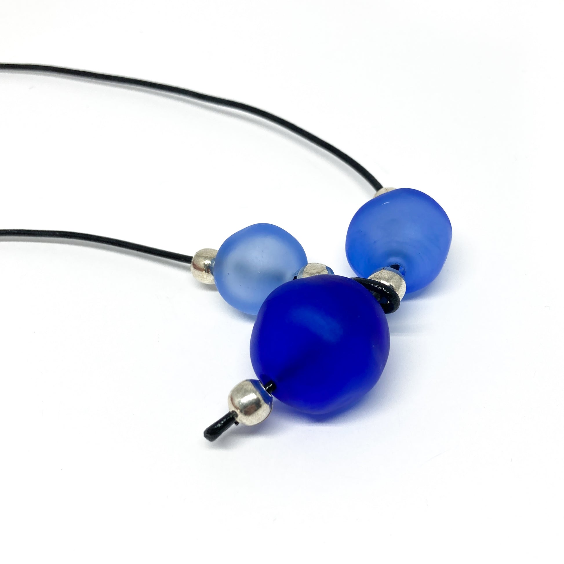 Black cord necklace with three blue beads and silver accents.