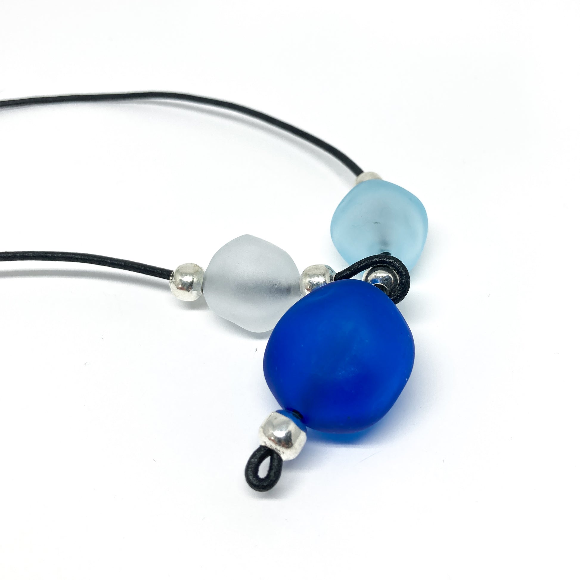 Black cord necklace with blue, light blue, and white beads, and silver accents.