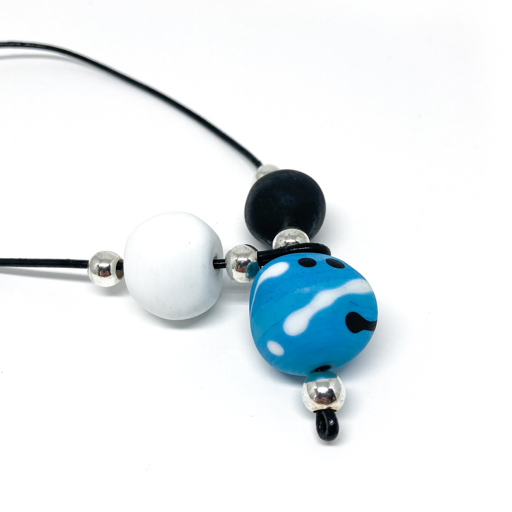 Black cord necklace with white, black, and blue patterned beads, and silver accents.