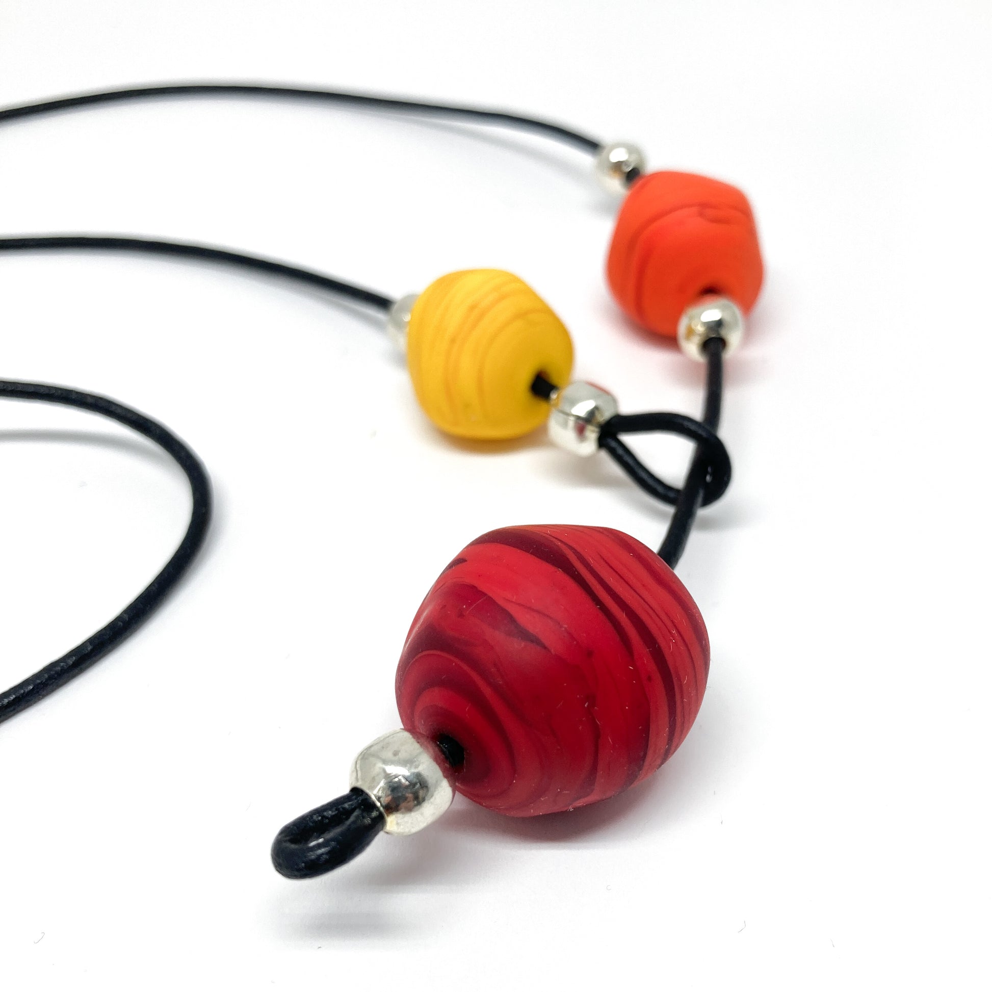 Black cord necklace with orange, yellow, and red beads.