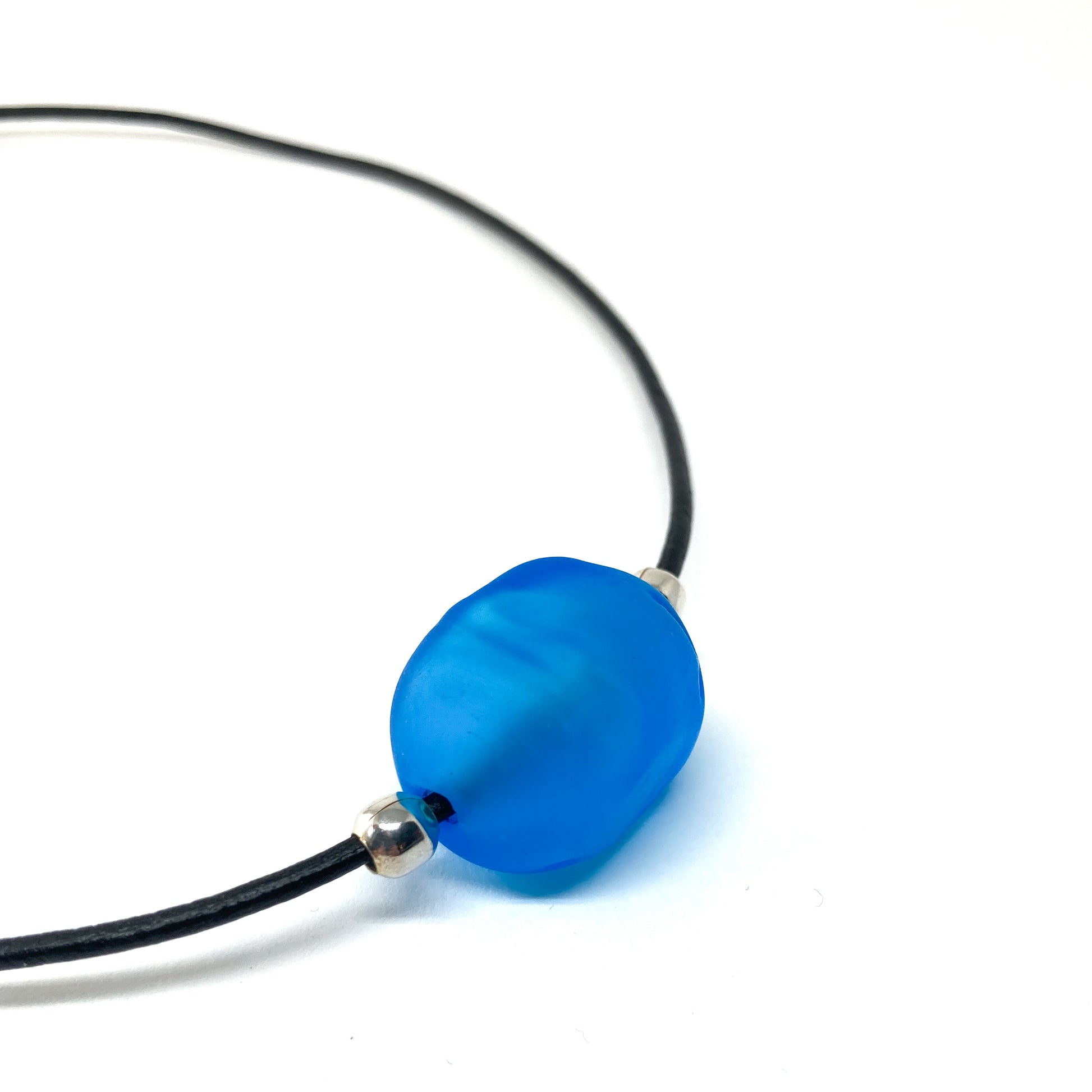 Black cord necklace with a blue bead and silver accents.