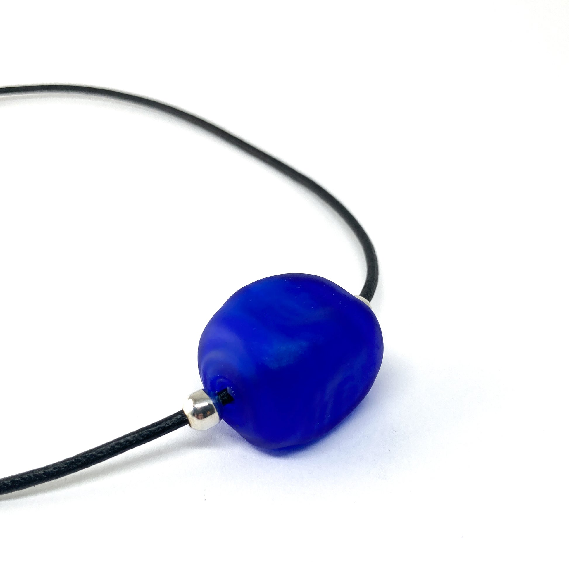 Black cord necklace with a blue bead and silver accents.