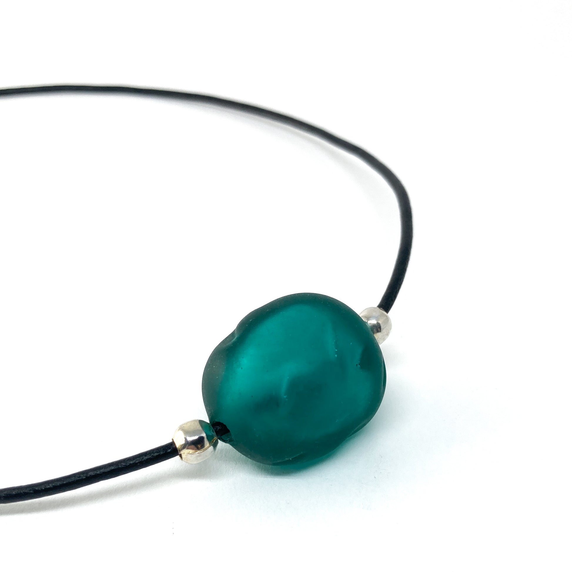 Black cord necklace with a dark teal bead and silver accents.