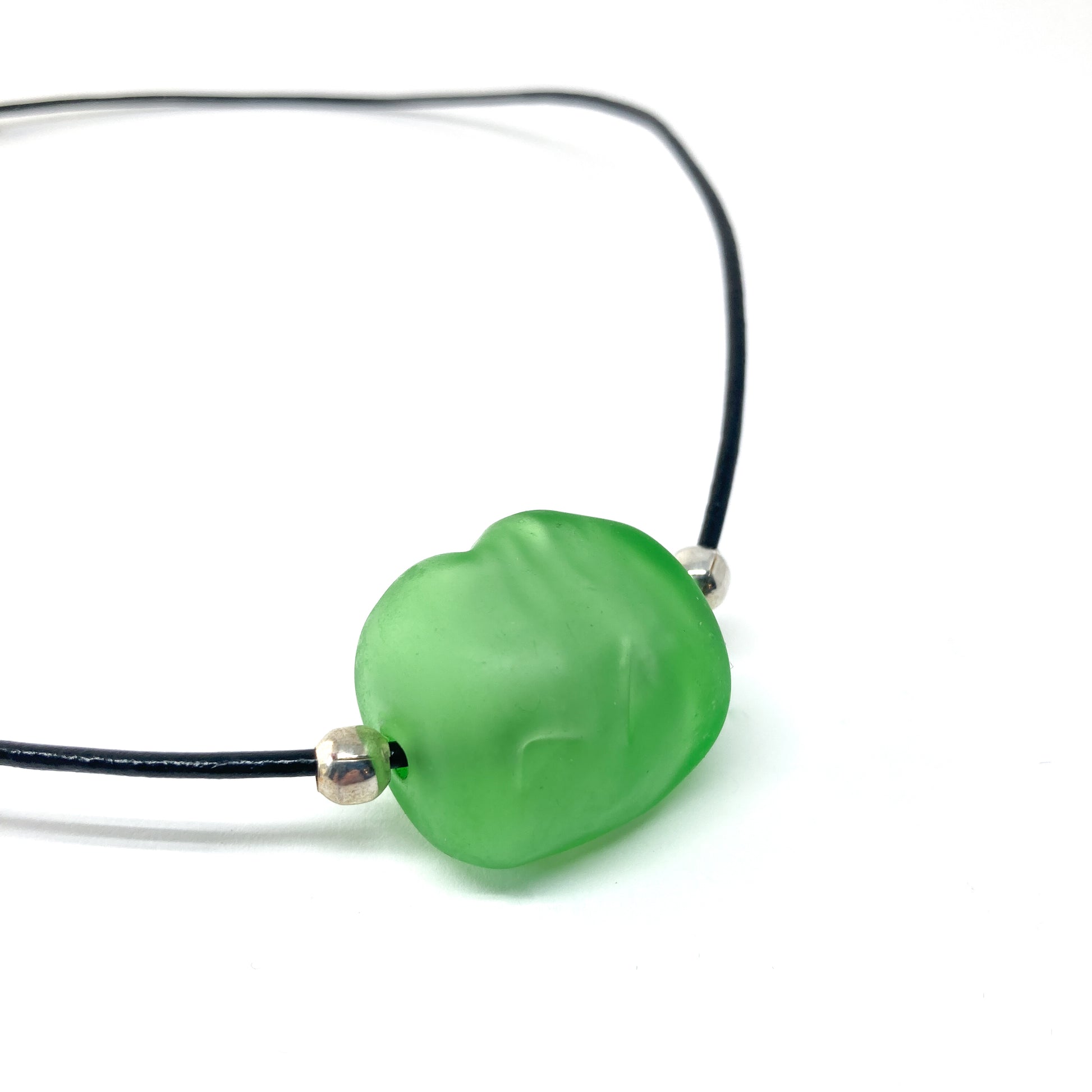 Black cord necklace with a green bead and silver accents.