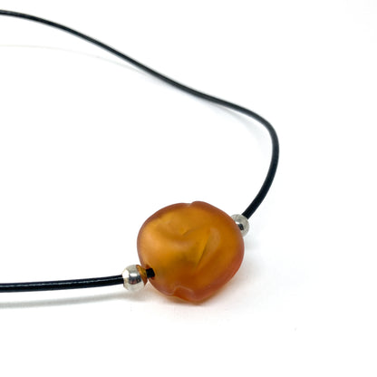 Black cord necklace with a orange bead and silver accents.