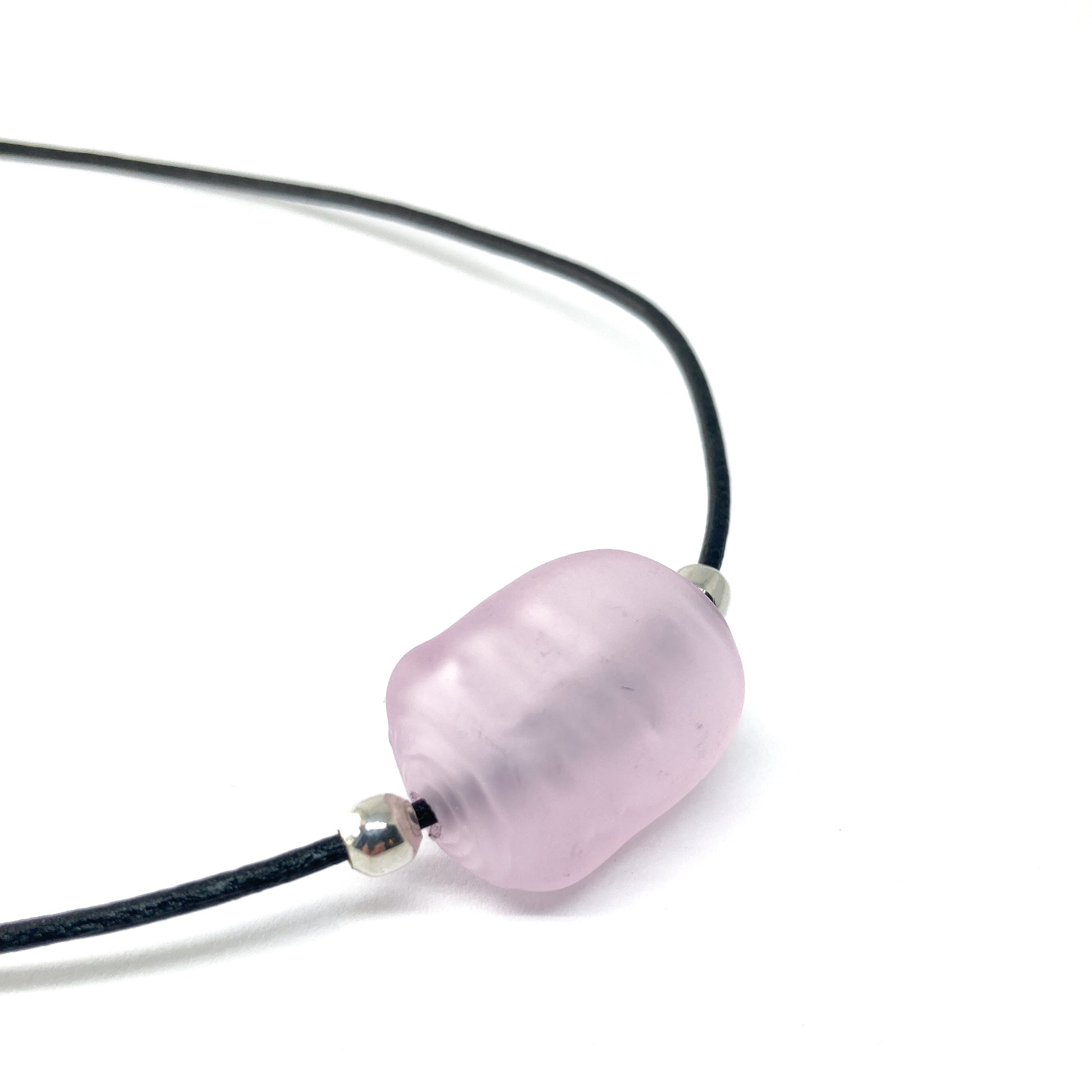 Black cord necklace with a light pink bead and silver accents.