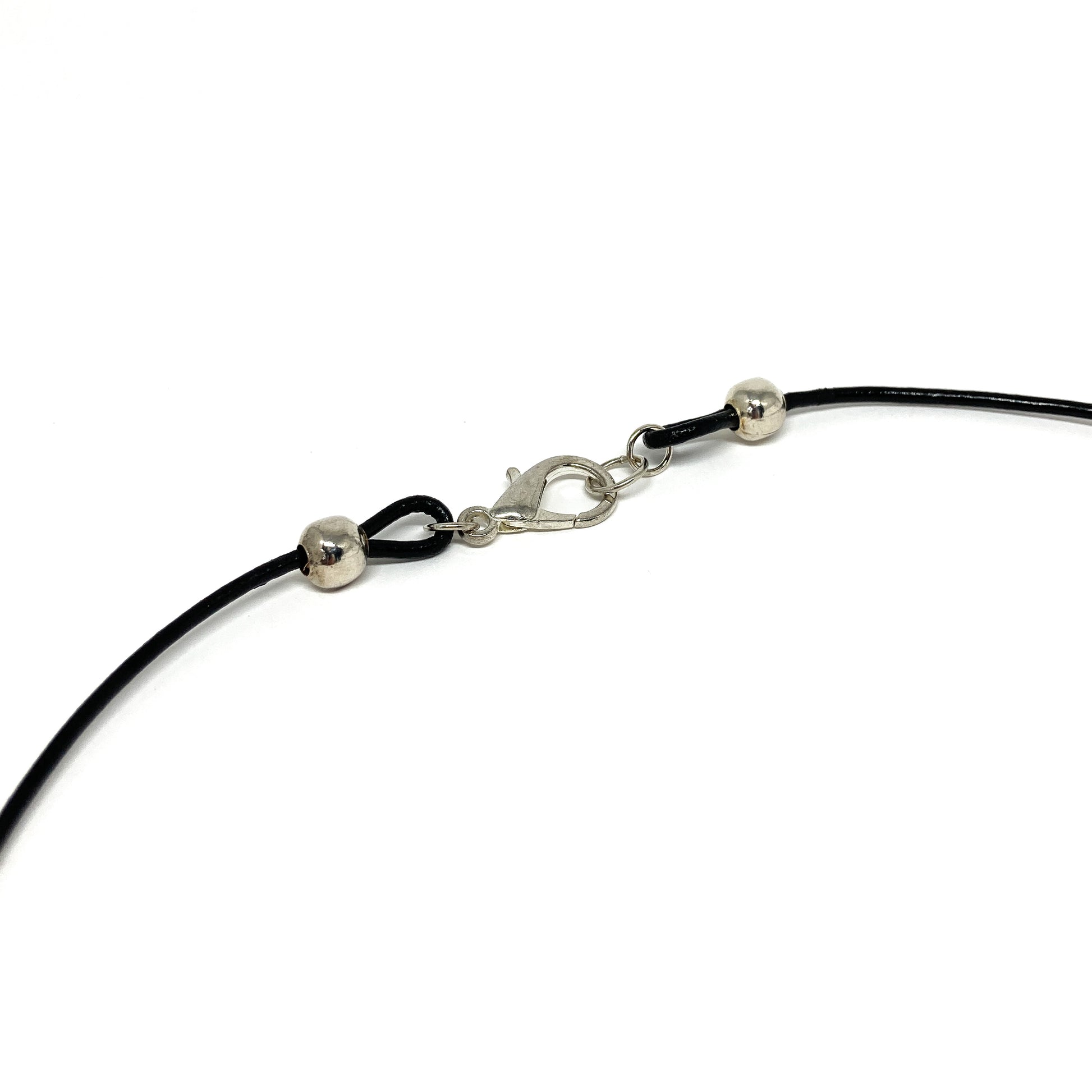 Close-up of a black cord necklace clasp with silver accents.
