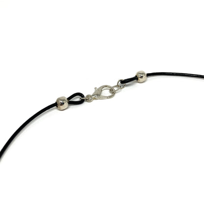 Close-up of a black cord necklace clasp with silver accents.