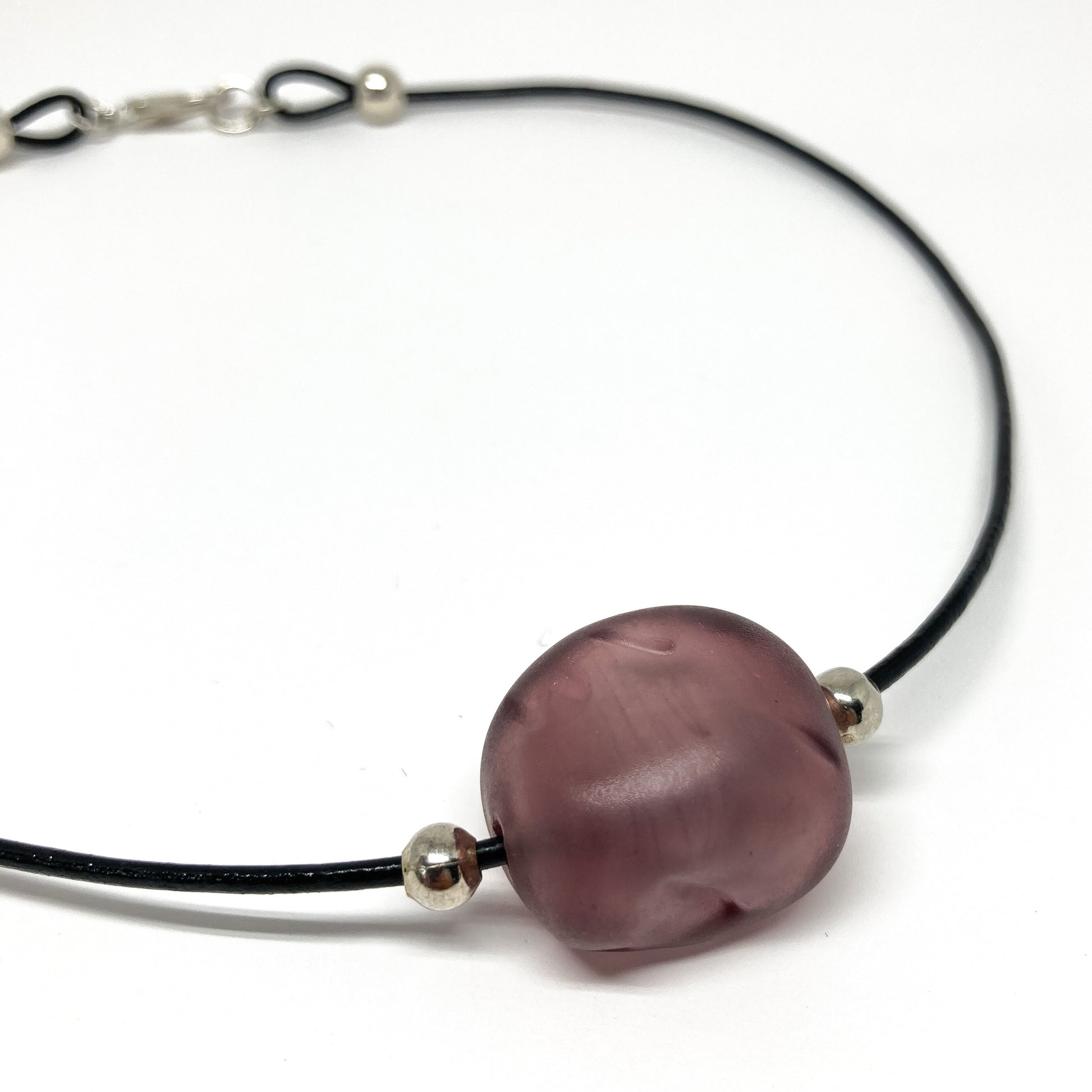 Black cord necklace with a purple bead and silver accents.