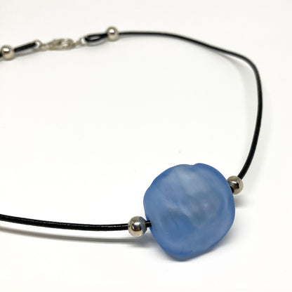 Black cord necklace with a blue bead and silver accents.