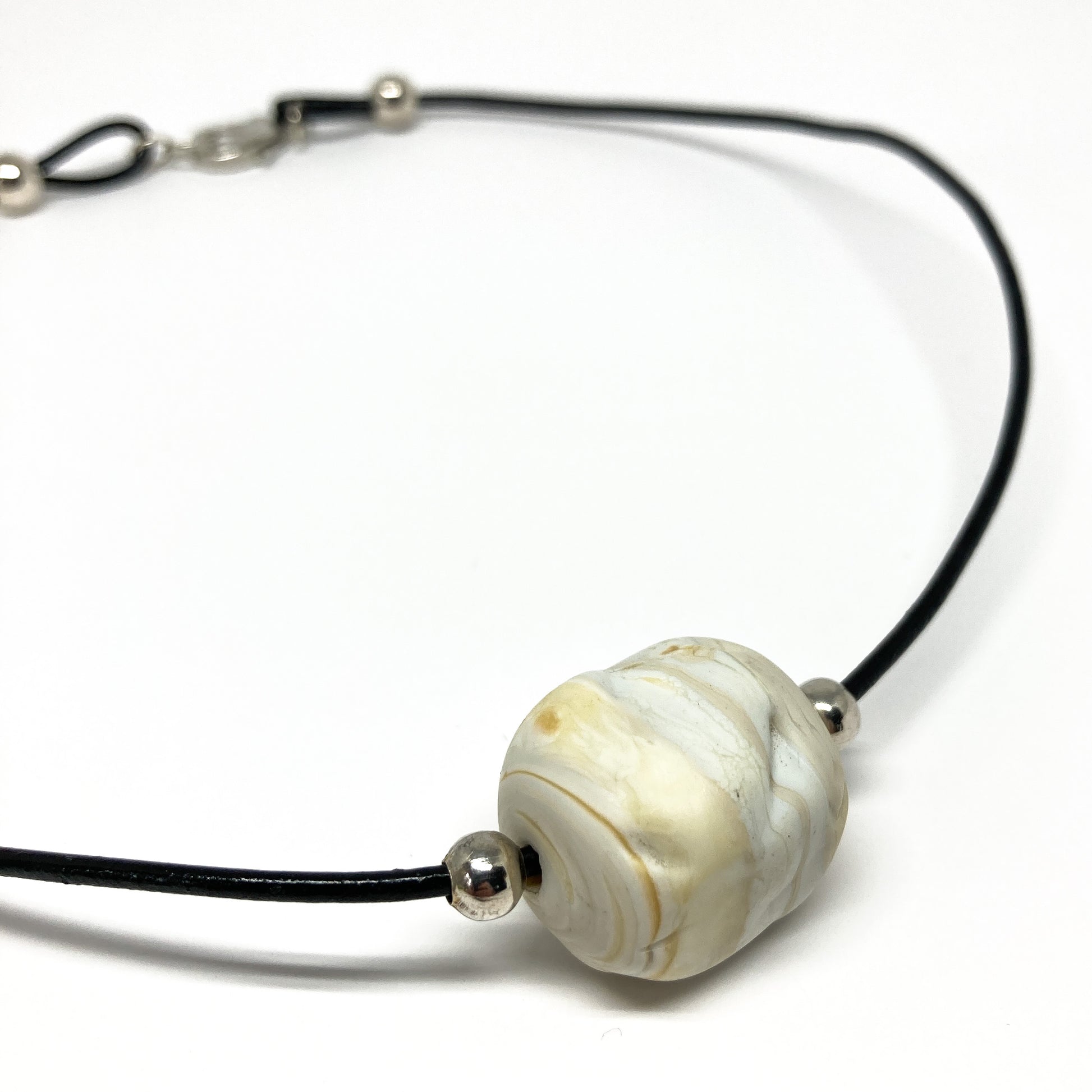 Black cord necklace with a white marbled bead and silver accents.