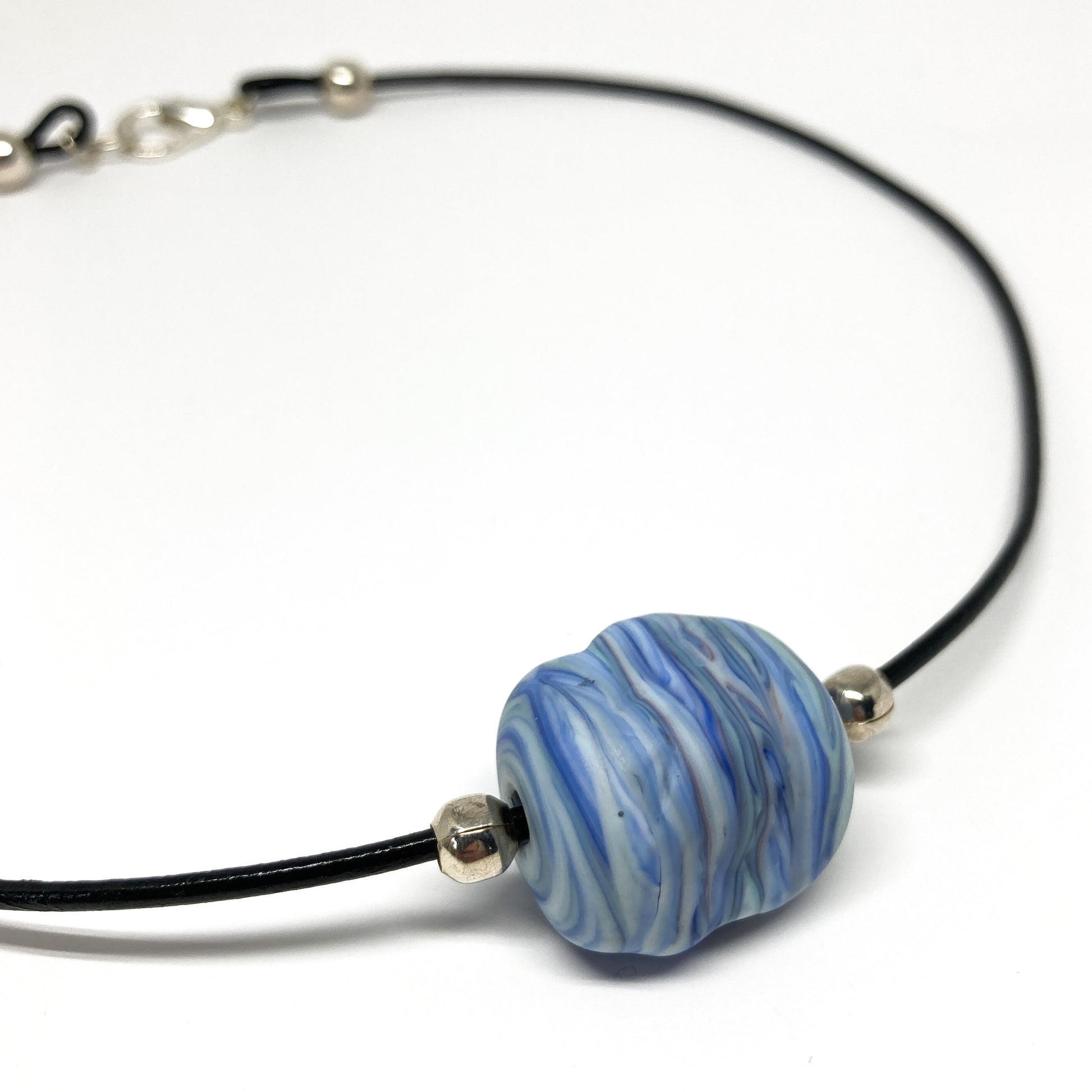 Black cord necklace with a blue striped bead and silver accents.
