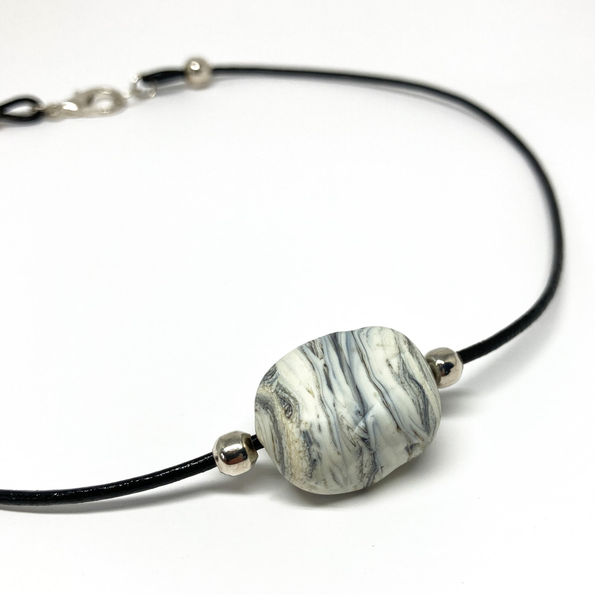 Black cord necklace with a gray striped bead and silver accents.