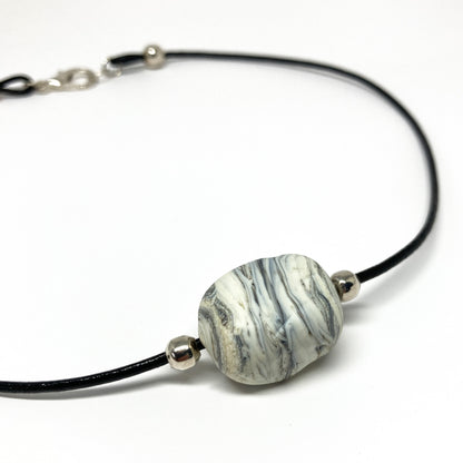 Black cord necklace with a gray striped bead and silver accents.