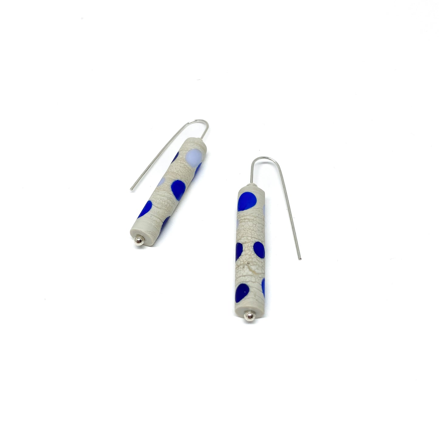 Two cylindrical earrings with blue dots, silver hooks, and small silver beads.
