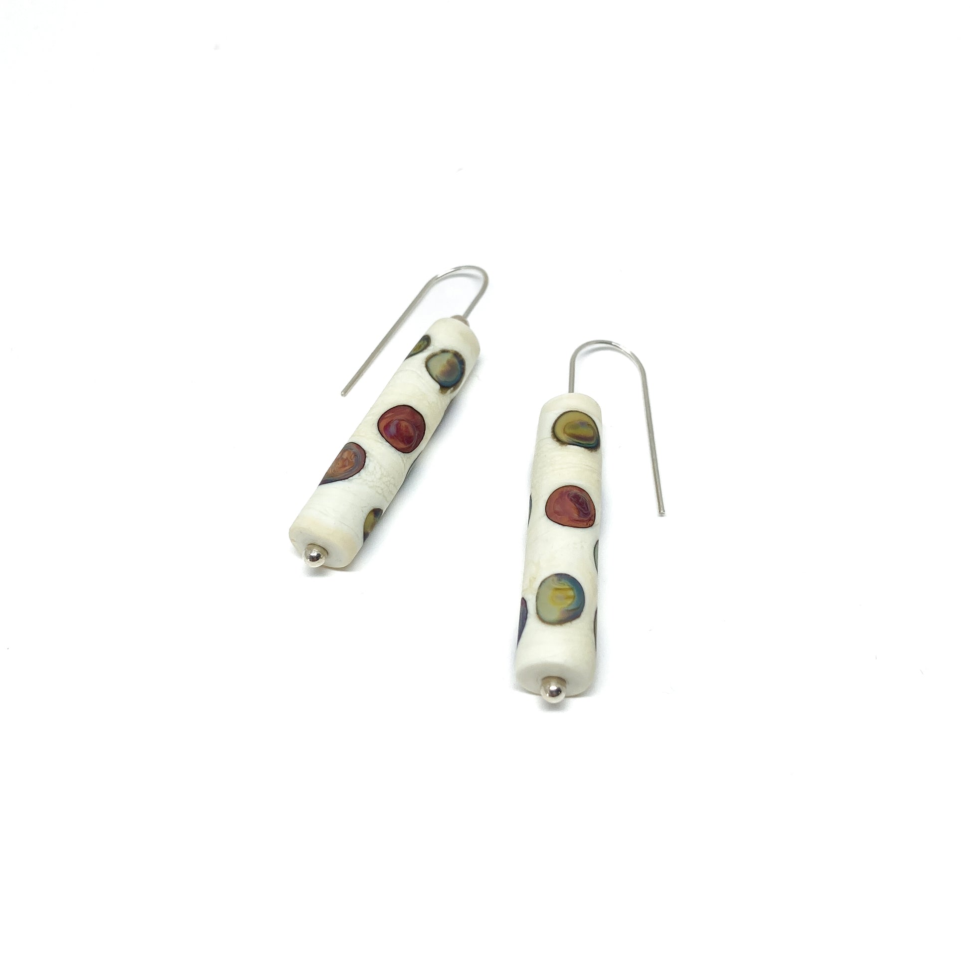 Two cylindrical earrings with multi-colored dots, silver hooks, and small silver beads.