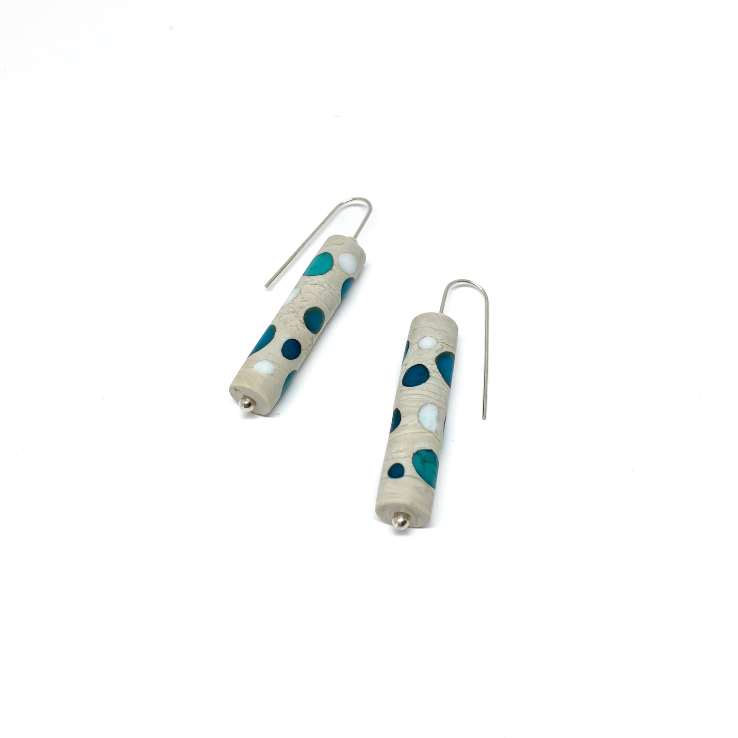 Two cylindrical earrings with teal and white dots, silver hooks, and small silver beads.