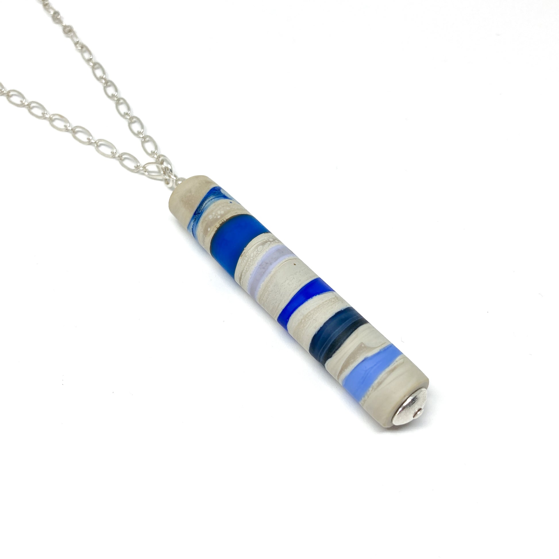 Silver chain necklace with a cylindrical pendant featuring blue, gray, and white stripes, and a small silver bead.