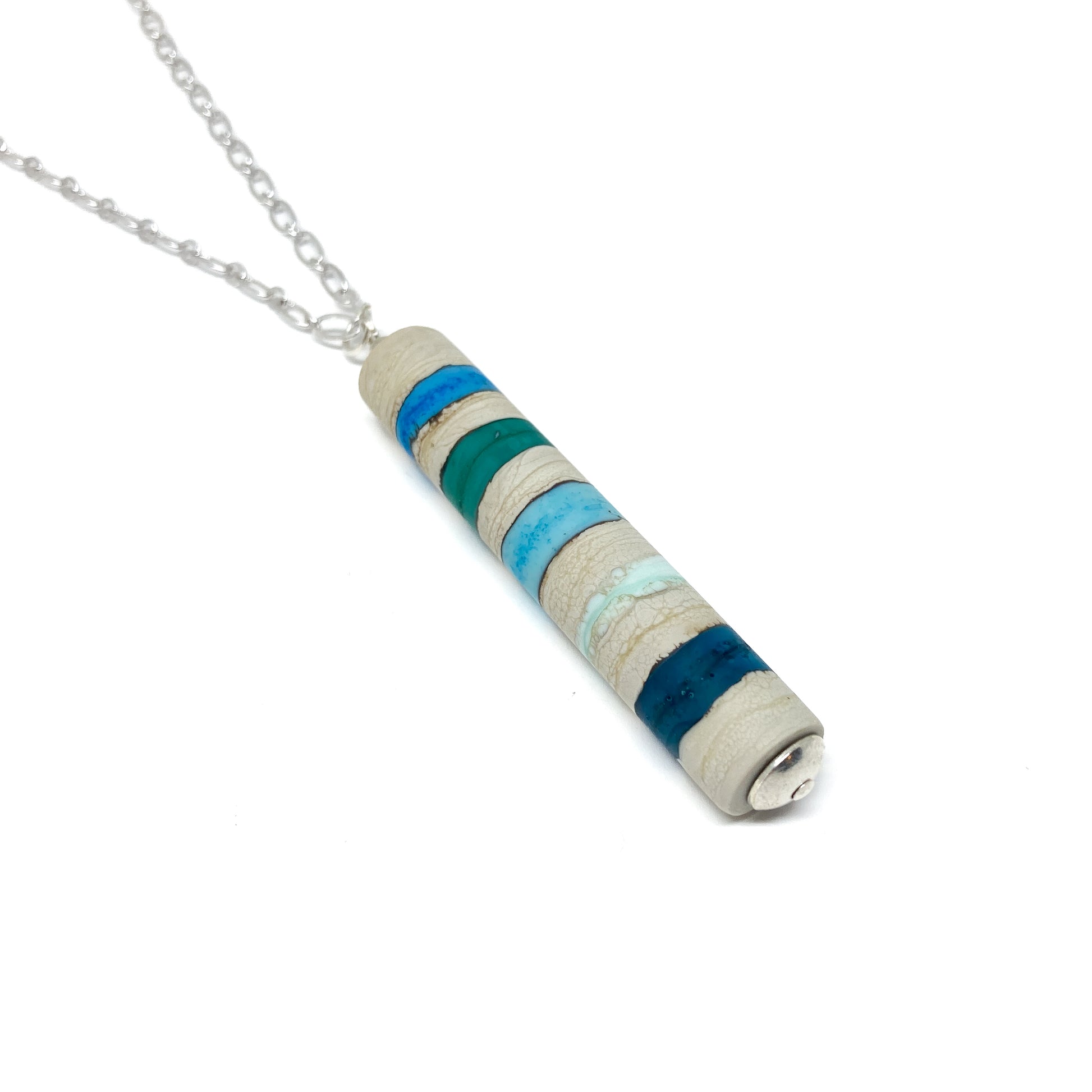Silver chain necklace with a cylindrical pendant featuring teal and blue stripes, and a small silver bead.