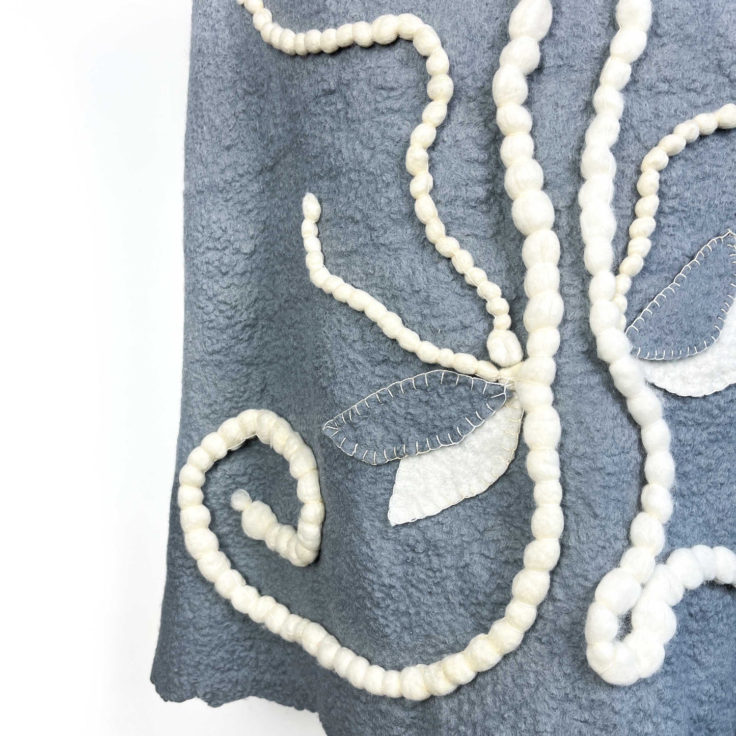 Close-up of the back of a gray Merino Wool Vest showing the cotton yarn floral design.