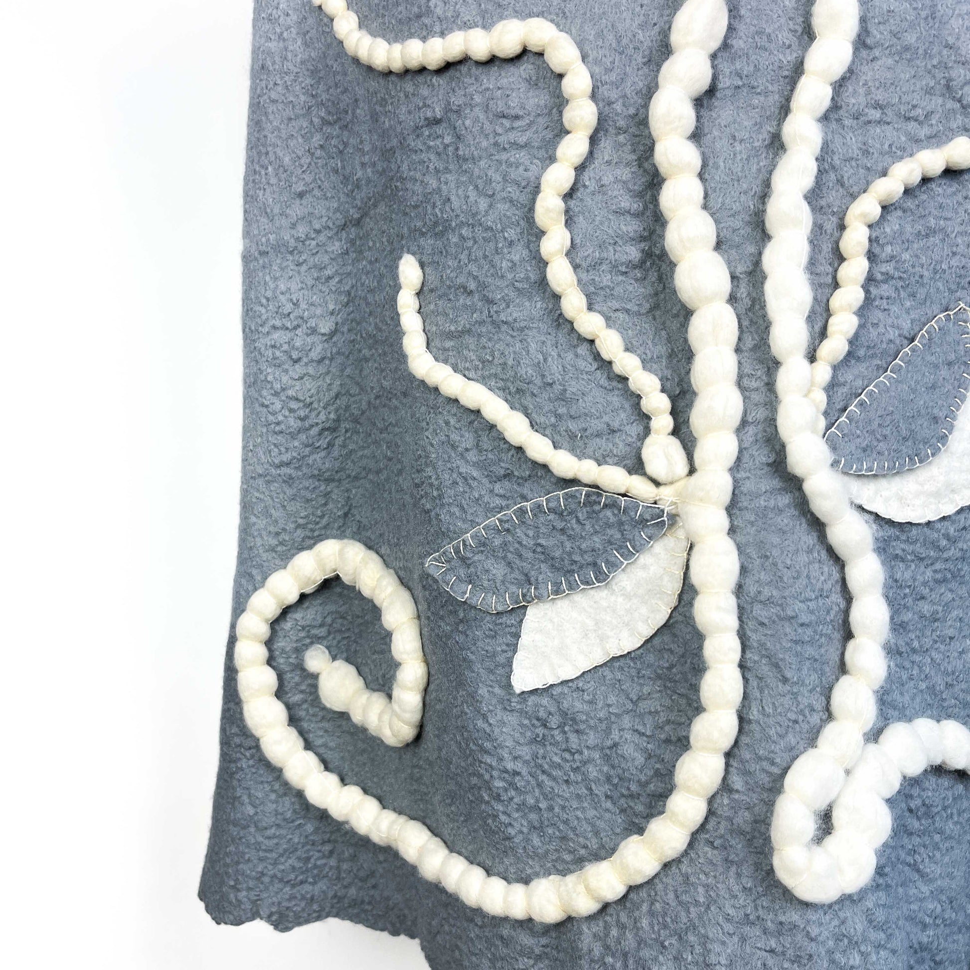 Close-up of the back of a gray Merino Wool Vest showing the cotton yarn floral design.