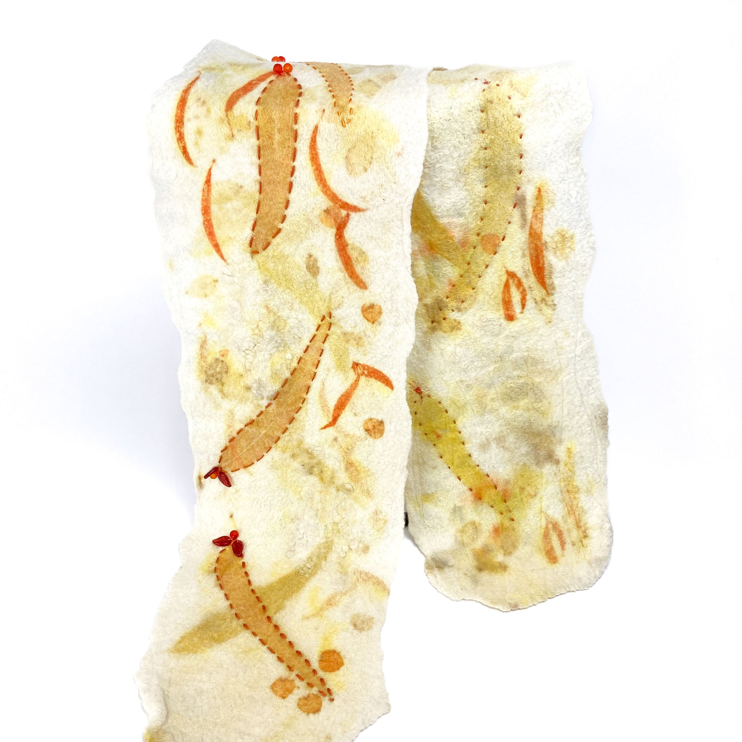 Soft eco-print scarf with organic orange and yellow patterns and small red details.