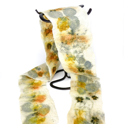 Eco Print Scarf draped on a black stand. The off-white scarf features organic shapes in muted yellows, greens, and soft oranges.