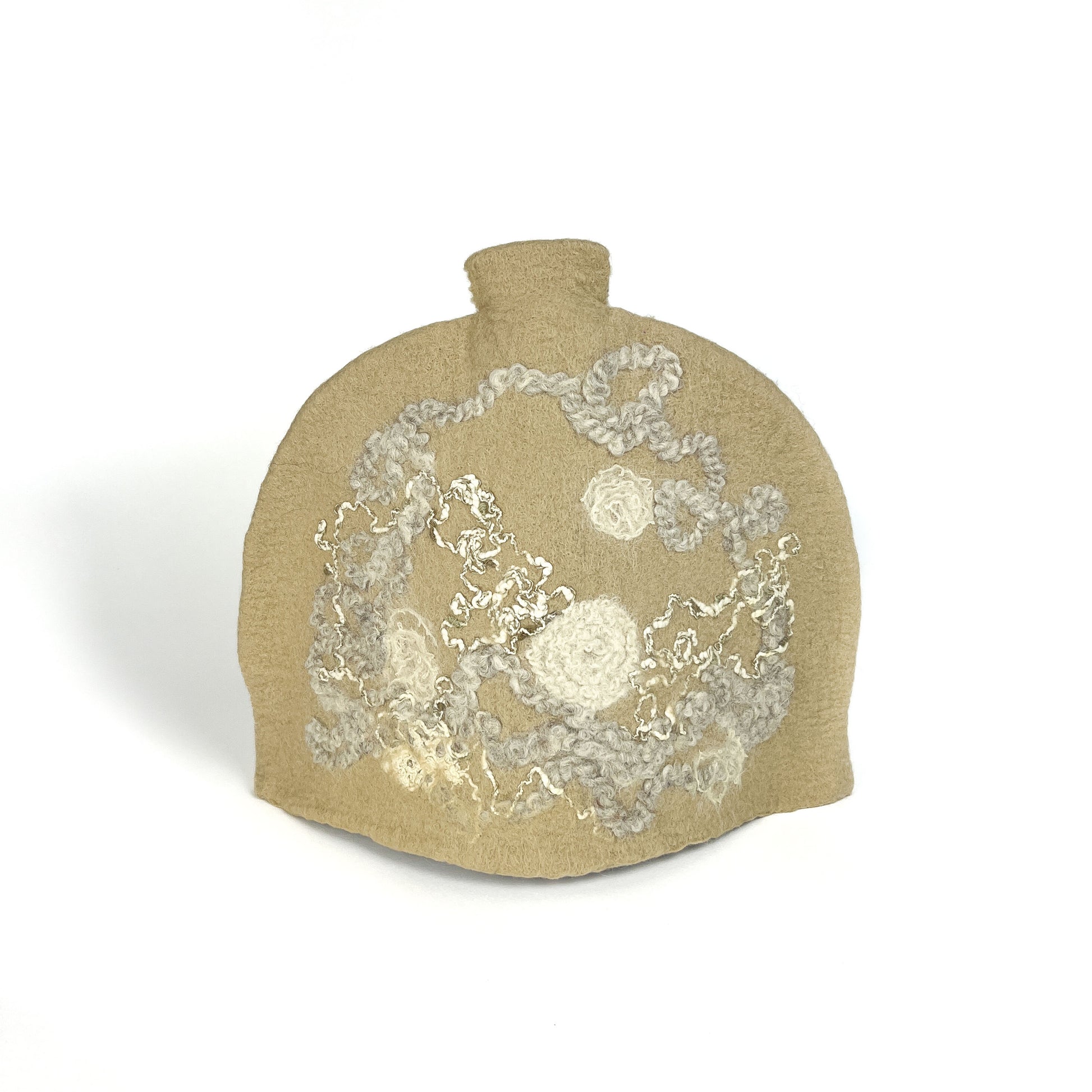 Beige felted teapot cozie with swirling, textured floral and abstract designs in white and gray.