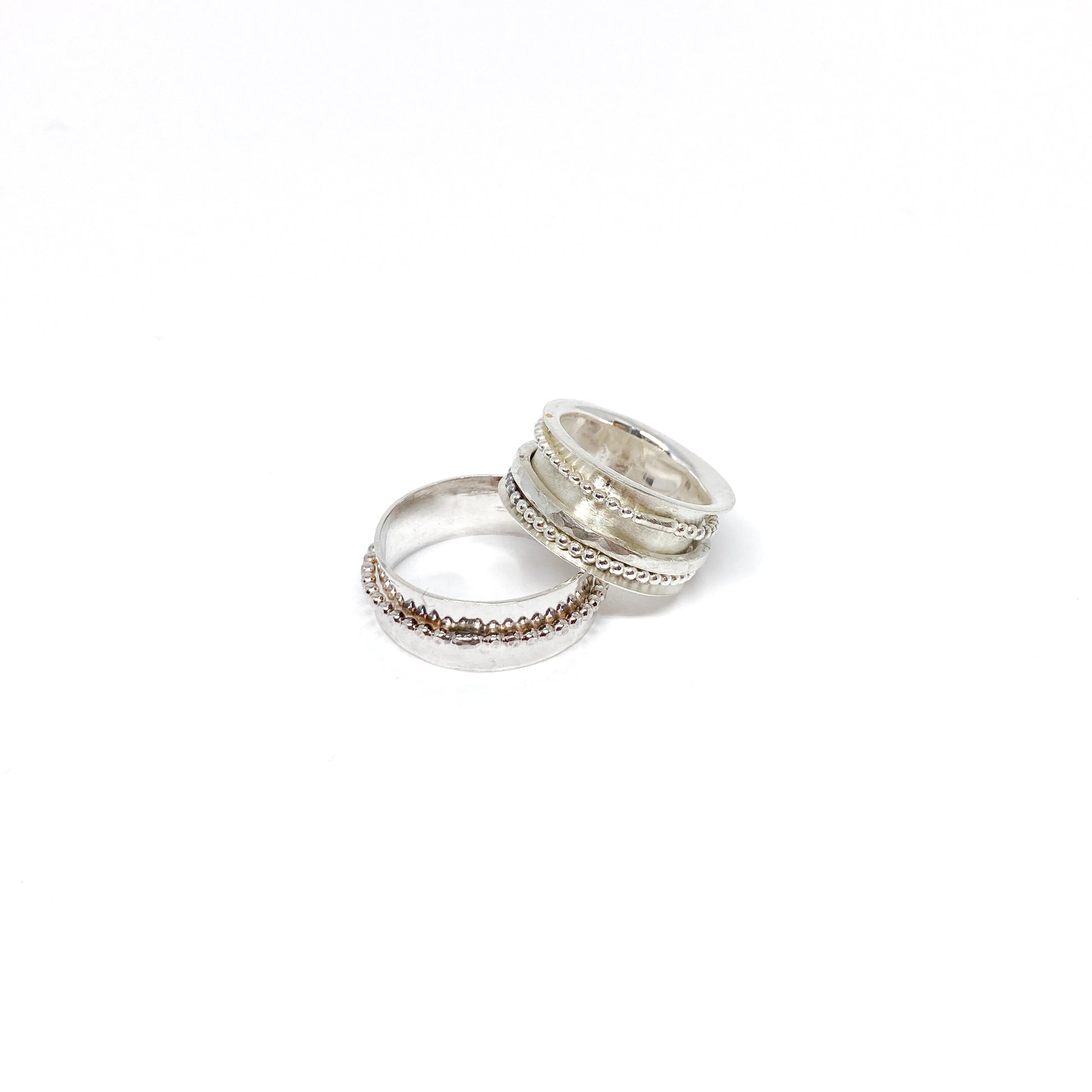 Two sterling silver spinner rings, one stacked, with beaded and textured spinning bands.