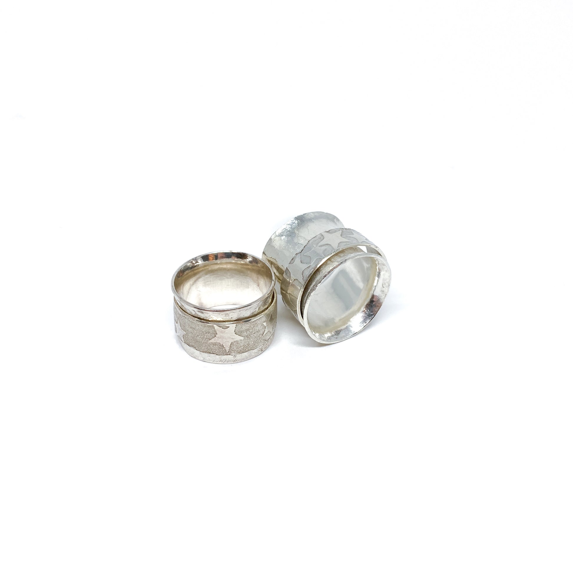 Two silver spinner rings, one stacked, featuring etched star designs on their outer bands.