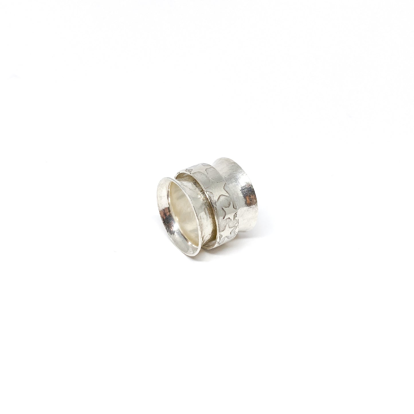 Silver spinner ring with a textured outer band adorned with etched star shapes.