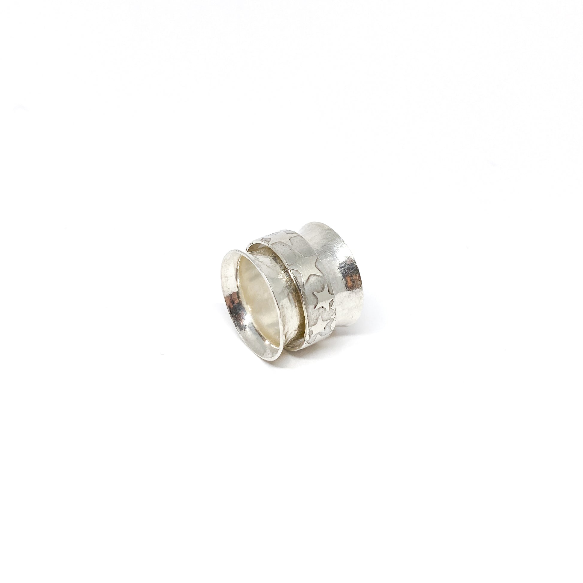 Silver spinner ring with a textured outer band adorned with etched star shapes.