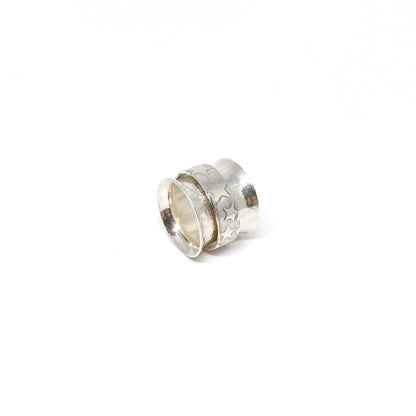 Silver spinner ring with a textured outer band adorned with etched star shapes.