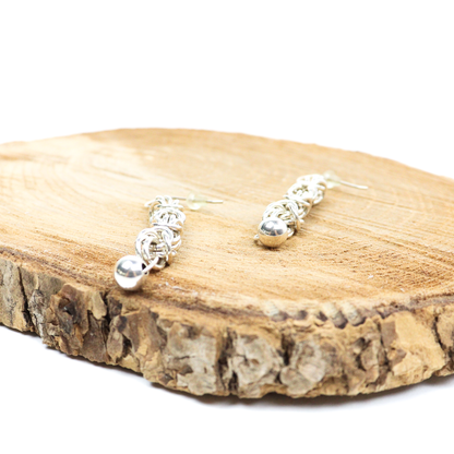 Side view of King Chain Dangle Earrings resting on wood, highlighting the intricate chainmail design.