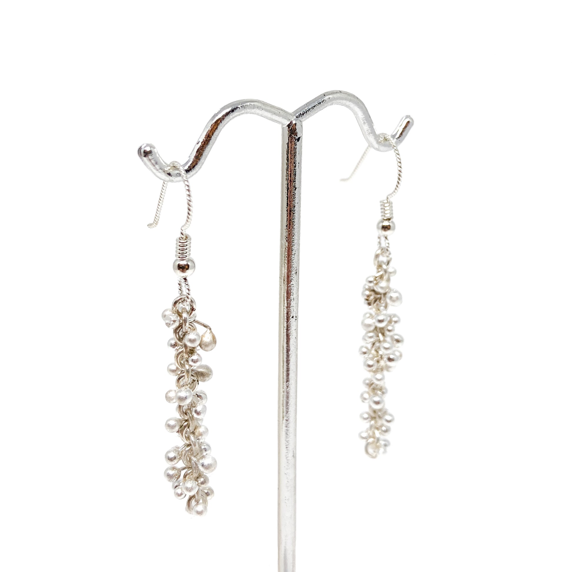 Side view of Baby Barbell Dangle Earrings hanging from a display stand, showcasing silver ball accents.