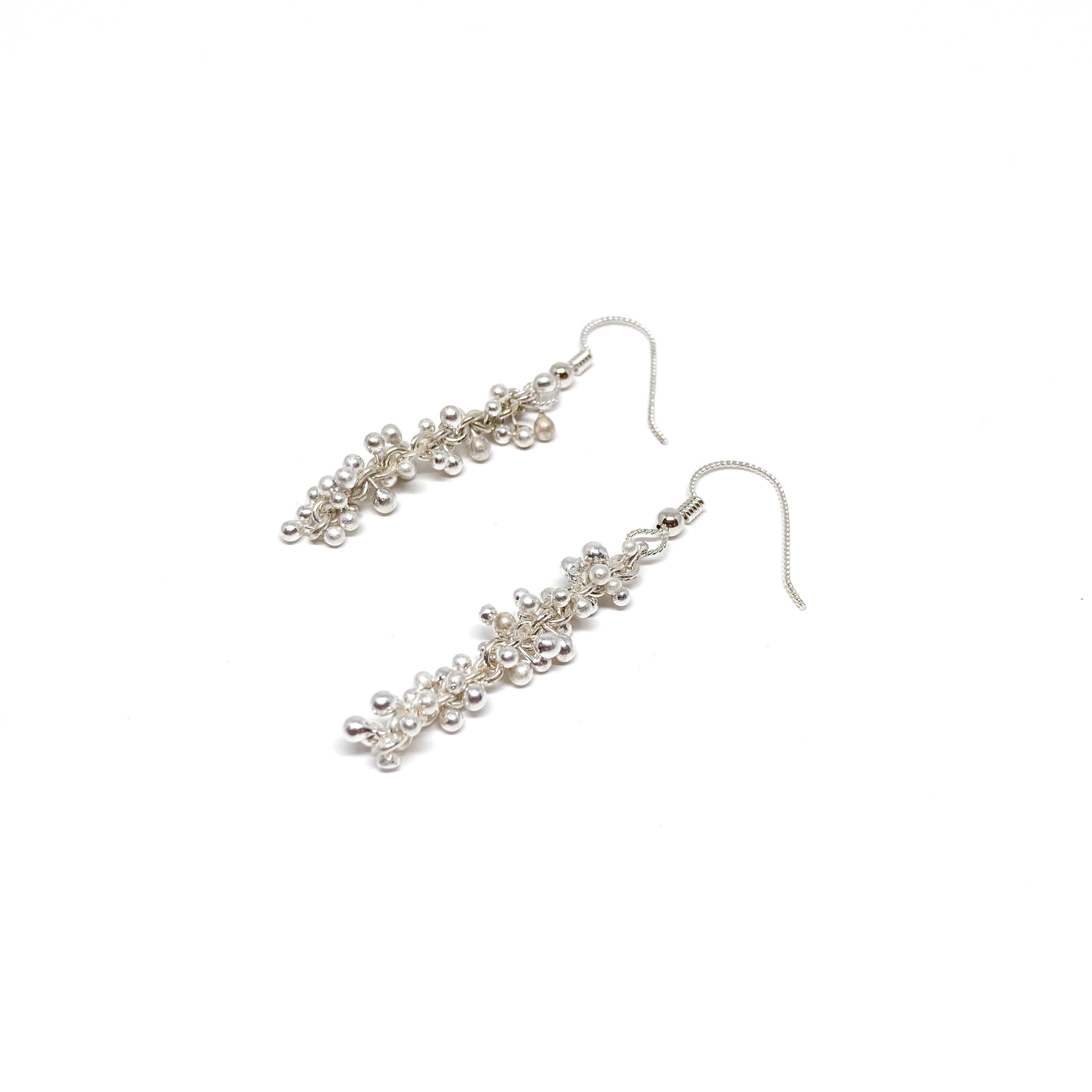 Baby Barbell Dangle Earrings laid flat, highlighting the detailed silver balls and woven chain design.