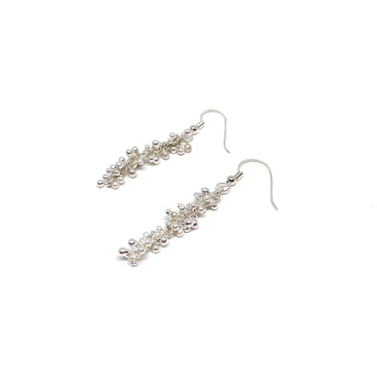 Baby Barbell Dangle Earrings laid flat, highlighting the detailed silver balls and woven chain design.