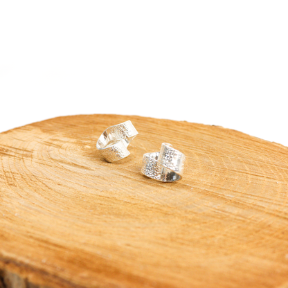 New York Button Studs placed on a wooden surface, emphasizing hammered silver and curved design.
