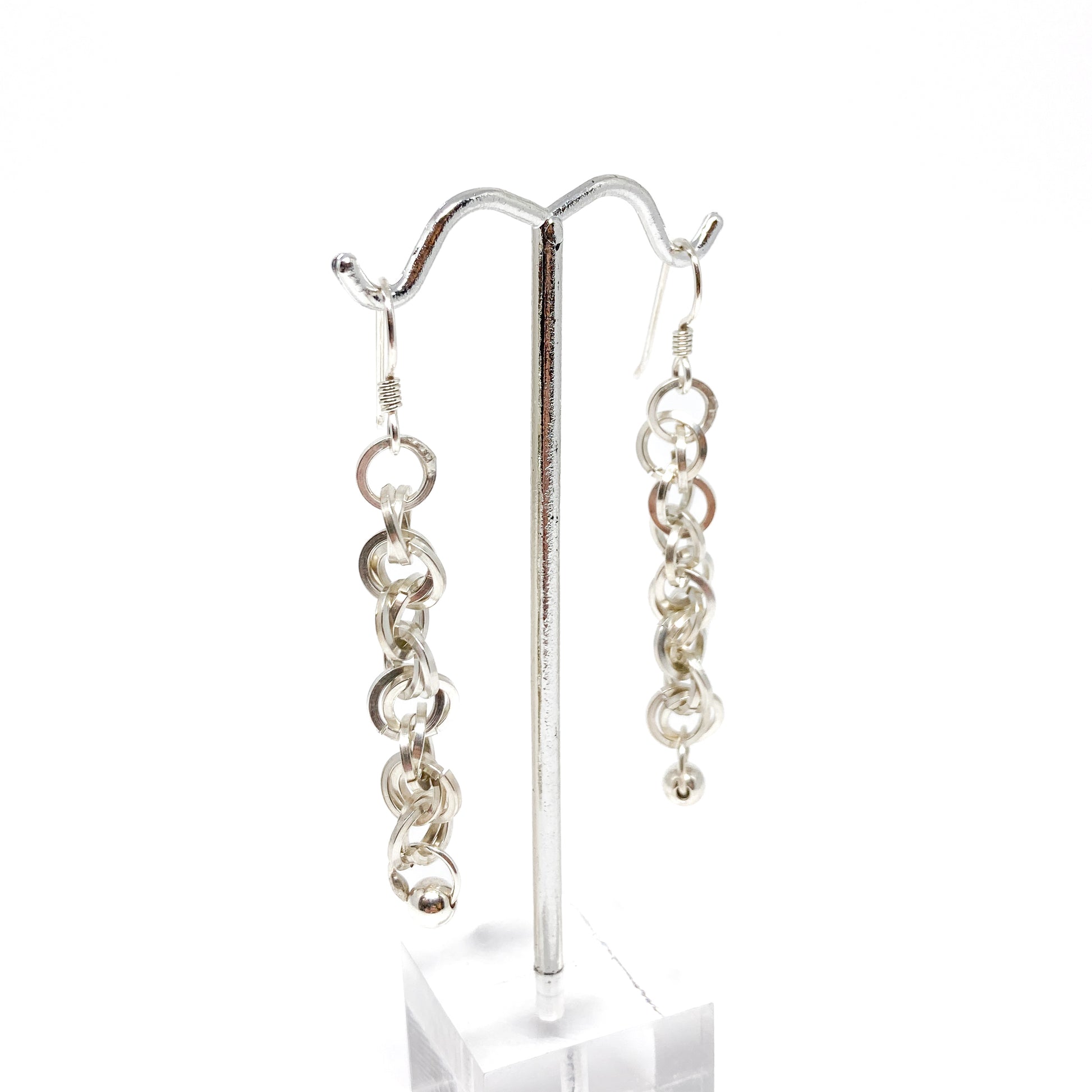 Two silver square chain dangle earrings with beads, displayed on a silver earring stand with clear acrylic base.