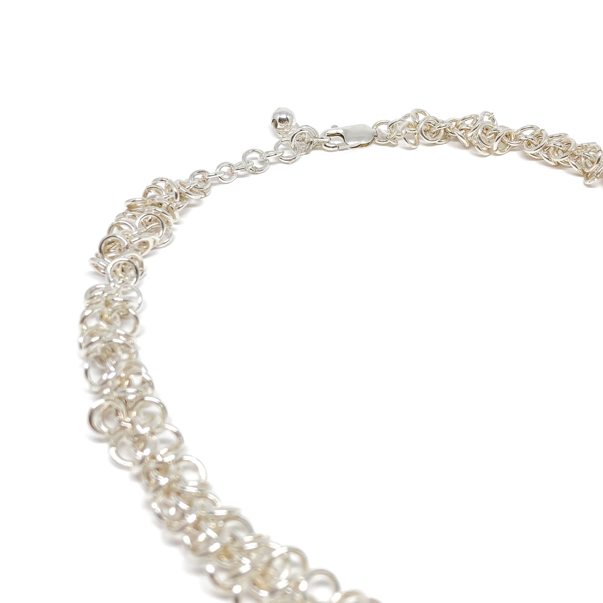 The clasp and extender chain of a silver Falling Link Necklace are visible, showcasing its adjustable length.