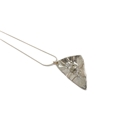 A silver pendant necklace with a triangular design and a central pearl accent. The pendant hangs from a delicate silver chain.