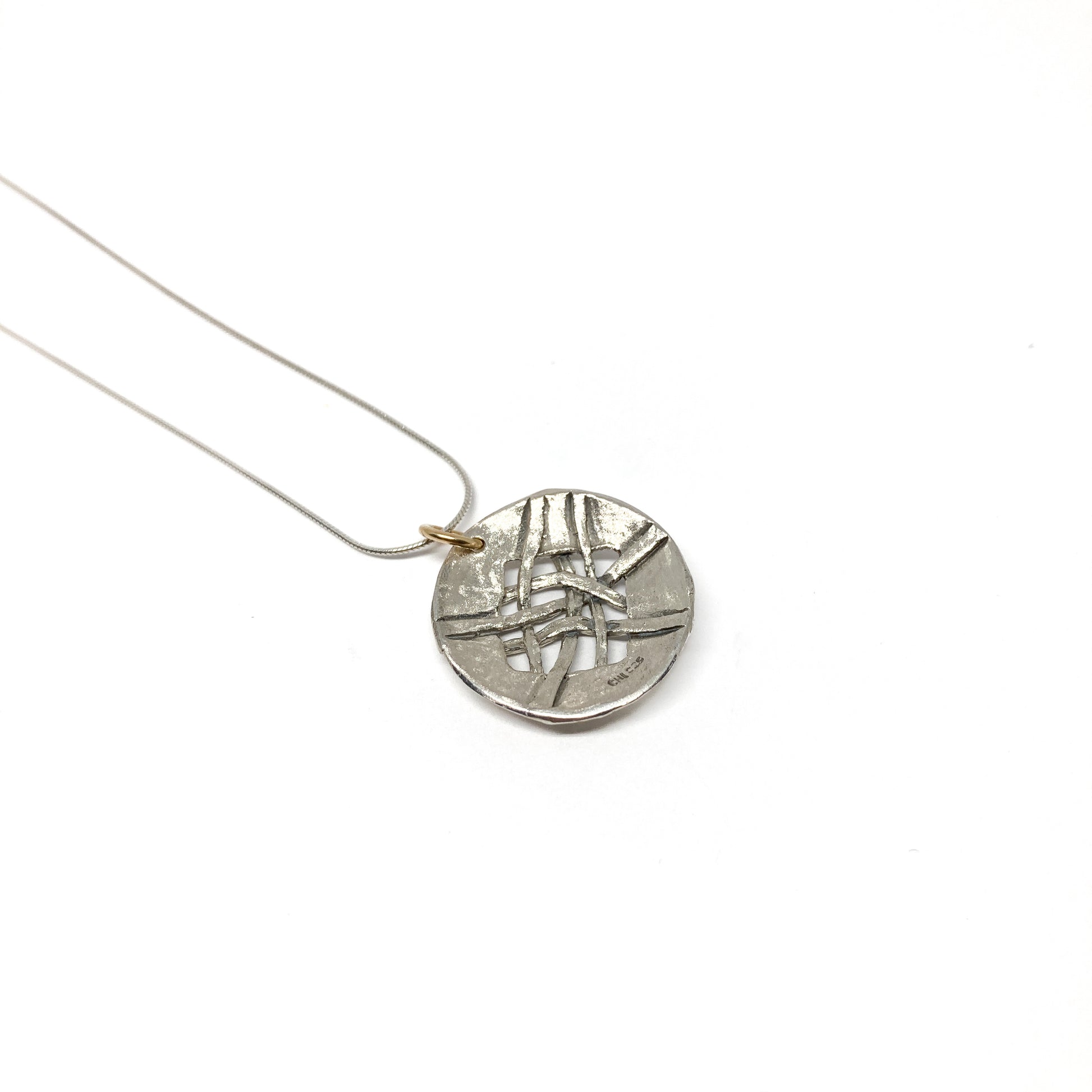 A silver pendant necklace with a circular disc pendant featuring a woven design. The pendant hangs from a delicate silver chain.