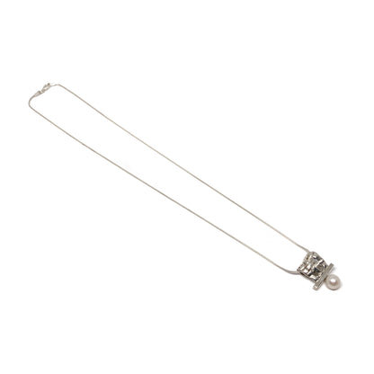A silver pendant necklace with a square woven design and a single pearl accent. The pendant hangs from a delicate silver chain.
