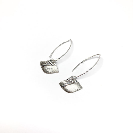 A pair of silver dangle earrings with a square woven design and a long, curved hook closure. The earrings have a textured finish.
