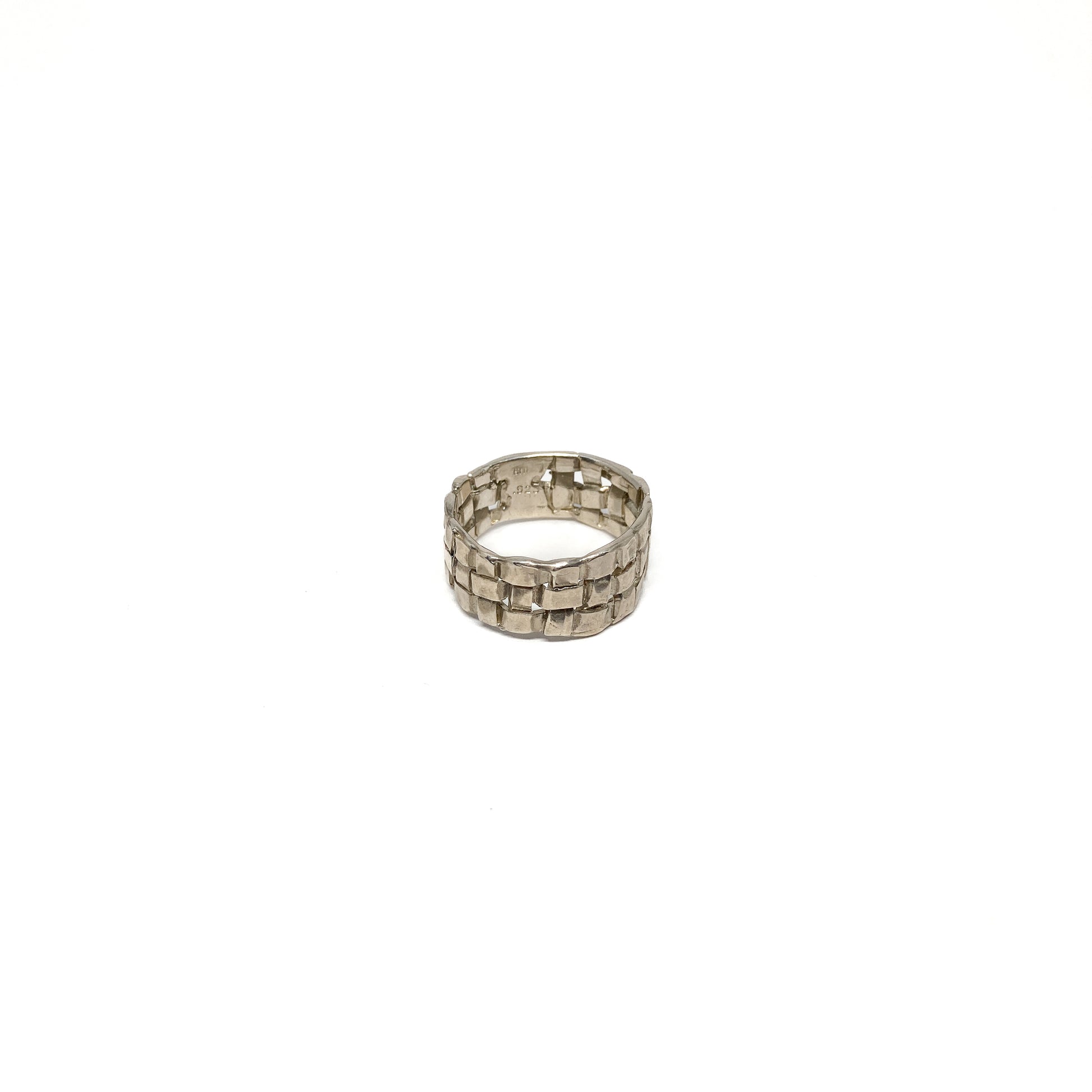 A chunky silver ring with a woven basket design. The ring has a wide band and a textured finish.
