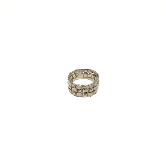 A chunky silver ring with a woven basket design. The ring has a wide band and a textured finish.