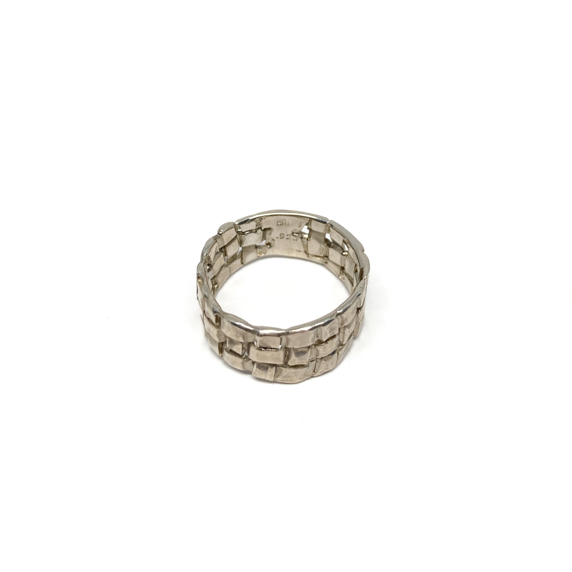A chunky silver ring with a woven basket design. The ring has a wide band and a textured finish.