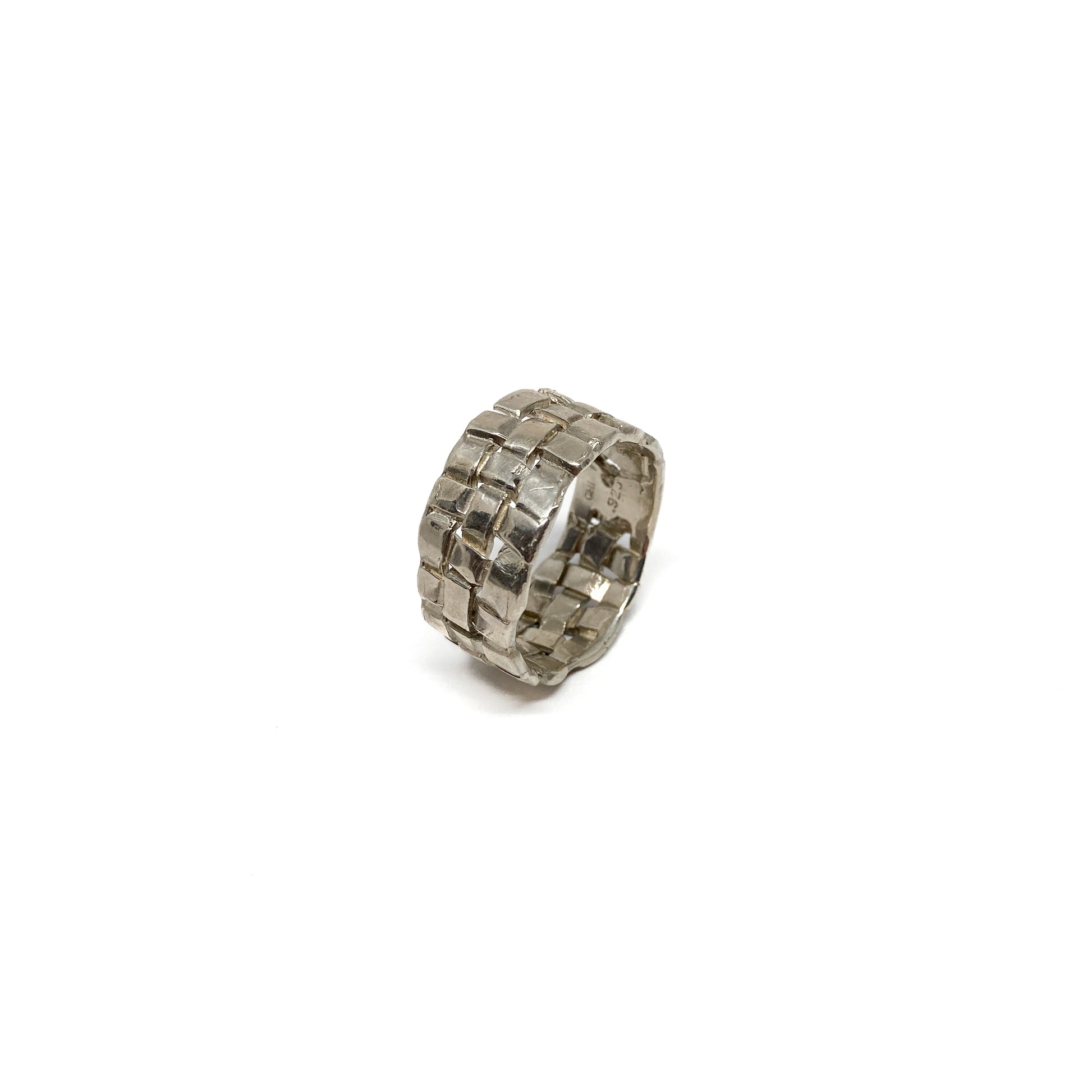 A chunky silver ring with a woven basket design. The ring has a wide band and a textured finish.
