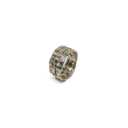 A chunky silver ring with a woven basket design. The ring has a wide band and a textured finish.