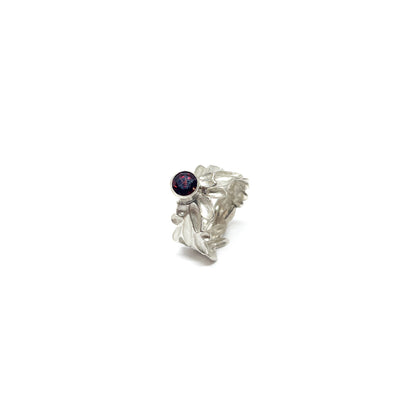 A textured sterling silver ring with abstract, organic shapes and a single, round deep red garnet gemstone setting.